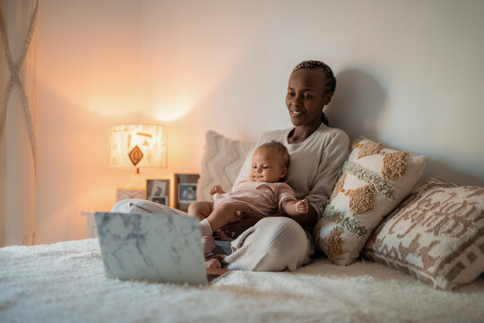 Woman watching cartoons on laptop with her baby 