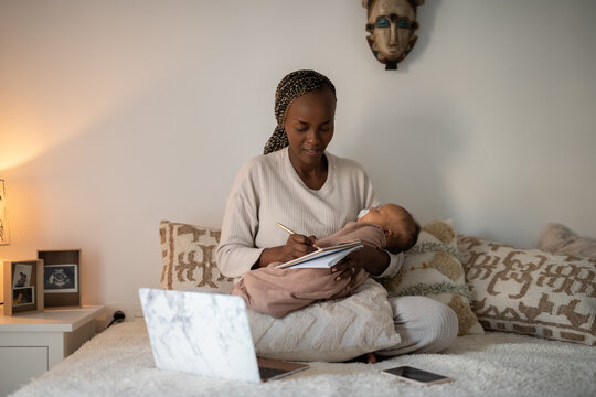 Woman working at home while holding sleeping baby 