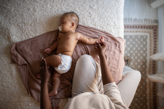 Mother stretching her baby back in bed 