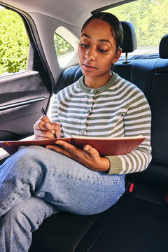 Young woman making notes in a car 