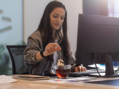 Woman at Desk Prepares Tea While Working on Computer