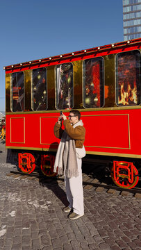 People take pictures at a bright red winter train in the town square