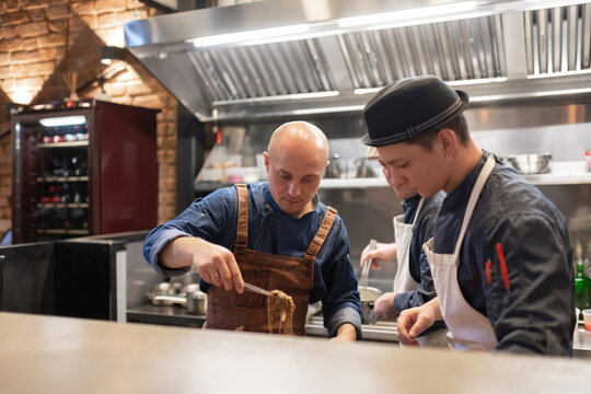 Men serving pasta in cafe