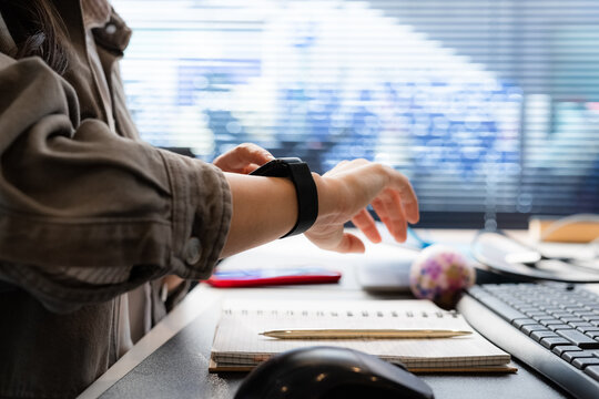 Woman using smartwatch app while working at office desk 