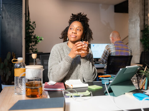 Woman thinking while drinking tea at office 