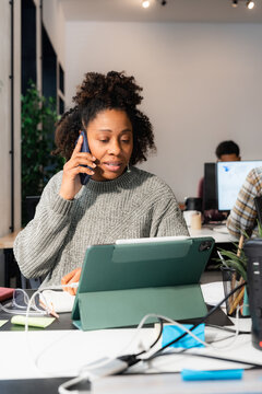 Woman Talking on Phone While Working at a Desk in Office