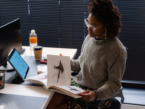 Woman reading art magazine at her office desk 