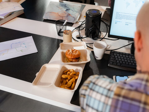 Man eating burger while working at office 