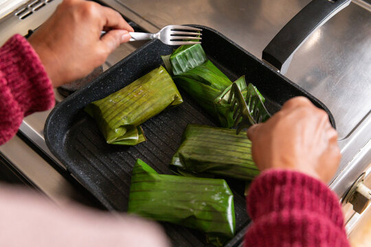 Cooking Nasi bakar or roasted rice with banana leaves as the wrappers