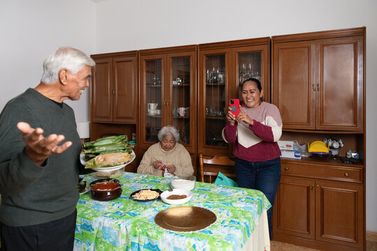 Daughter taking a photo of her playful elderly father with Nasi Bakar