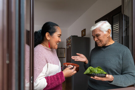 Joyful senior man and adult daughter presenting traditional food