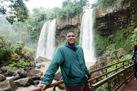 Man Stands Near Waterfall in Jungle During Cloudy Day