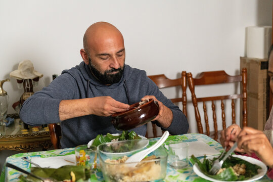 Man serving shredded chicken side dish for Nasi Bakar at home
