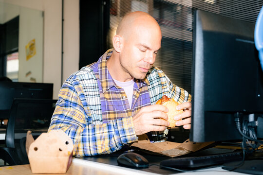 Man Eats Burger at Office Desk During Work Hours