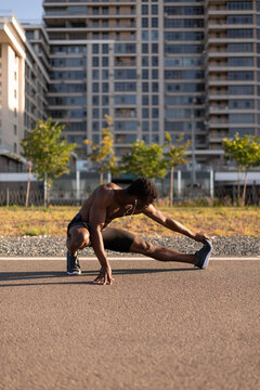 Unrecognizable Black male stretching feet before running