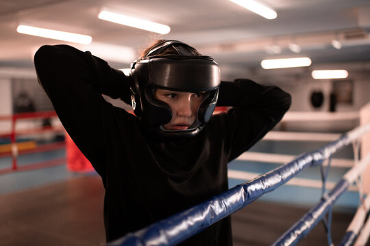 Female boxer putting on helmet before fight