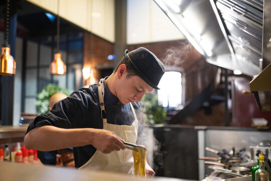 Young chef boiling tagliatelle in cafe