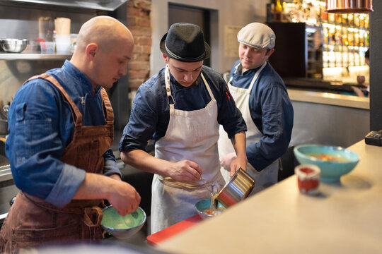 Men watching colleague serving soup