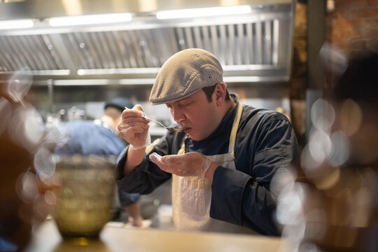 Male cook trying dish in cafe kitchen
