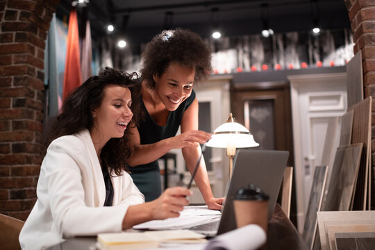 Happy diverse female designers using laptop