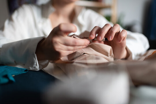 Cropped seamstress unstitching fabrics working at home