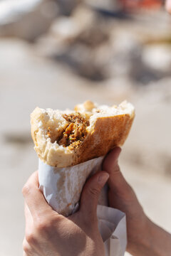 Hands holding bitten wrap sandwich