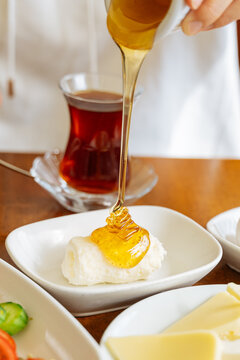 Honey being poured over clotted cream with tea