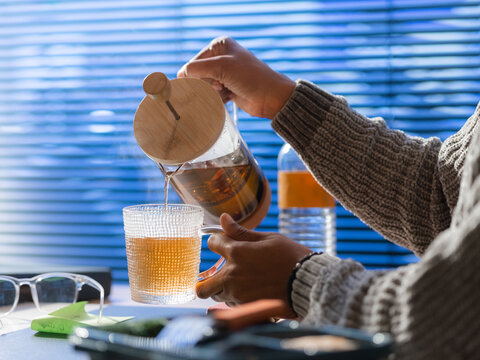 Woman pouring tea in cup at office 