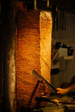 Doner kebab being sliced on vertical rotisserie