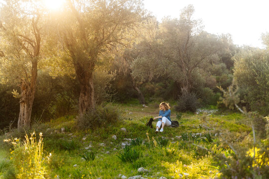 Woman sitting in sunlit olive grove