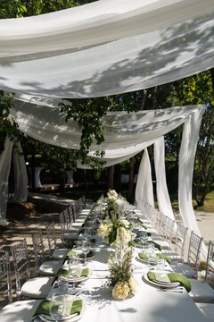 Table setting under silk canopy at wedding reception in cozy yard