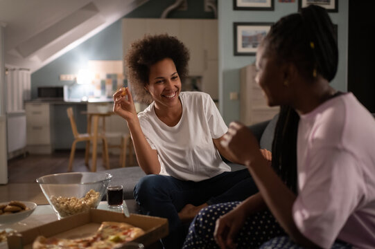 Black girlfriends having delivered pizza and chatting on home party