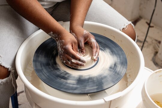 Hands shaping clay on wheel