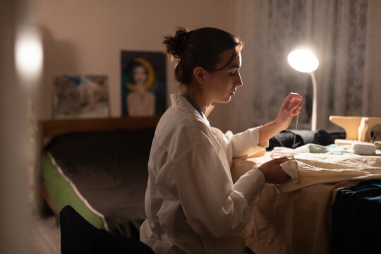 Seamstress sewing at home in lamplight