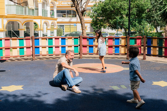 Father and Children Play Together in a Playground on a Sunny Day