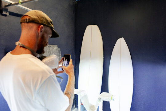Surfboard shaper photographing surfboard blanks in shaping room