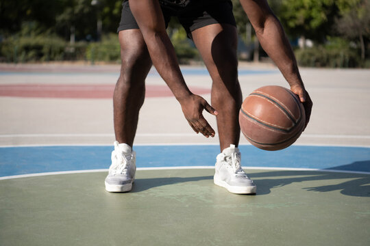 Cropped black sportsman dribbling basketball ball