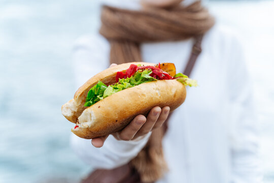 Person presenting fish sandwich with vegetables