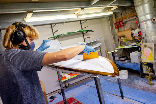 Worker applying resin to surfboard in Australia