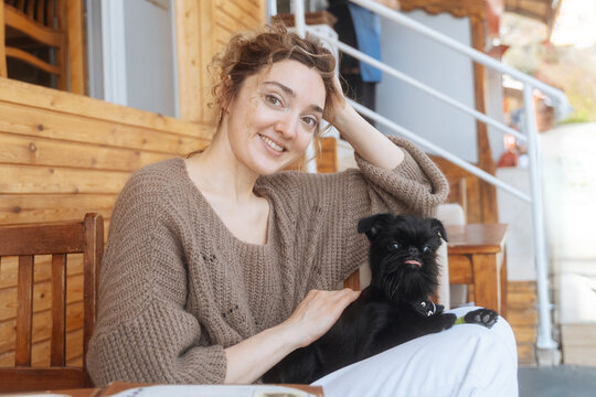 Smiling woman sitting with small black dog