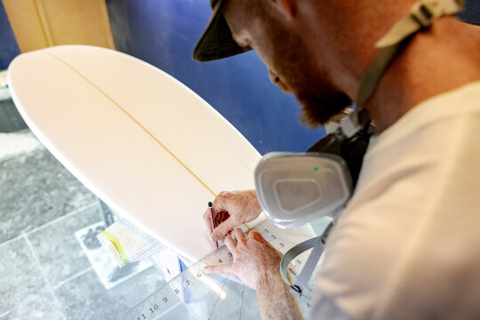Surfboard shaper marking fin layout in Australia