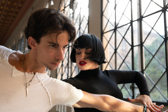 Passionate man and woman dancing against window