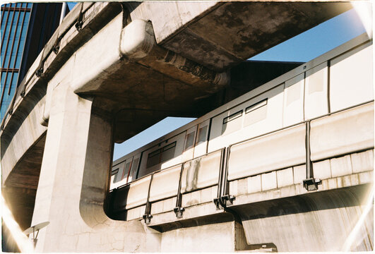 Train moves under a concrete structure in an urban area