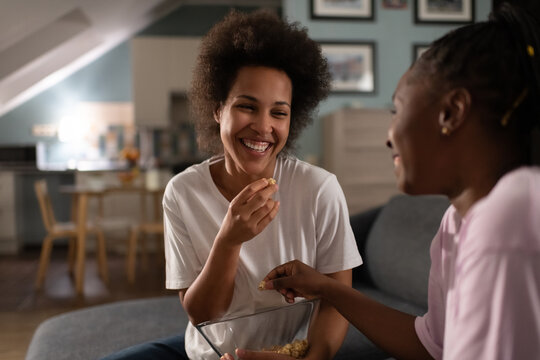 Diverse happy girlfriends having popcorn while enjoying home party