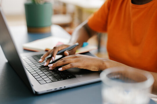 Person Typing on Laptop at a Table Indoors During the Day