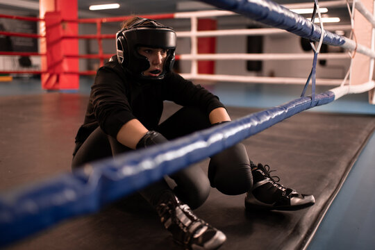 Tired female boxer resting after match in gym
