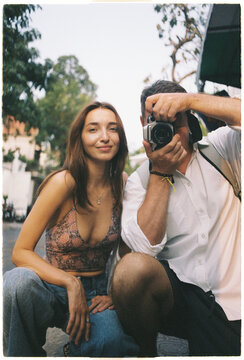 Woman and man pose for a camera in a city street on a sunny day