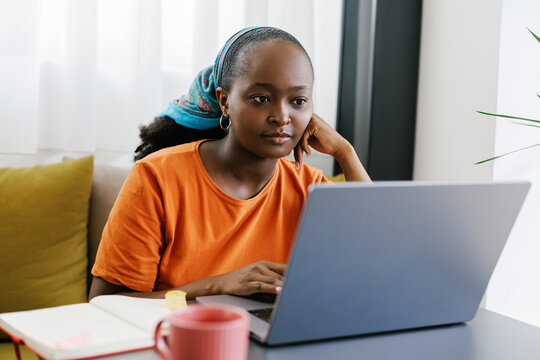 Portrait of young black woman working on laptop in cafe 