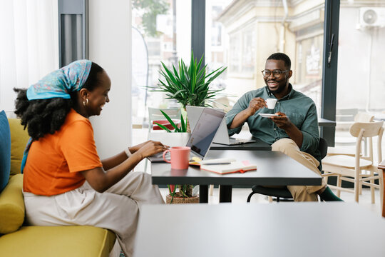 Friends Enjoy Coffee and Work in a Bright Cafe During the Day