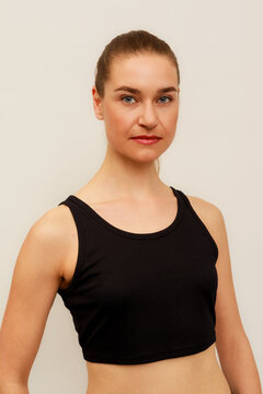 Model Poses in a Black Top in Front of Plain Background